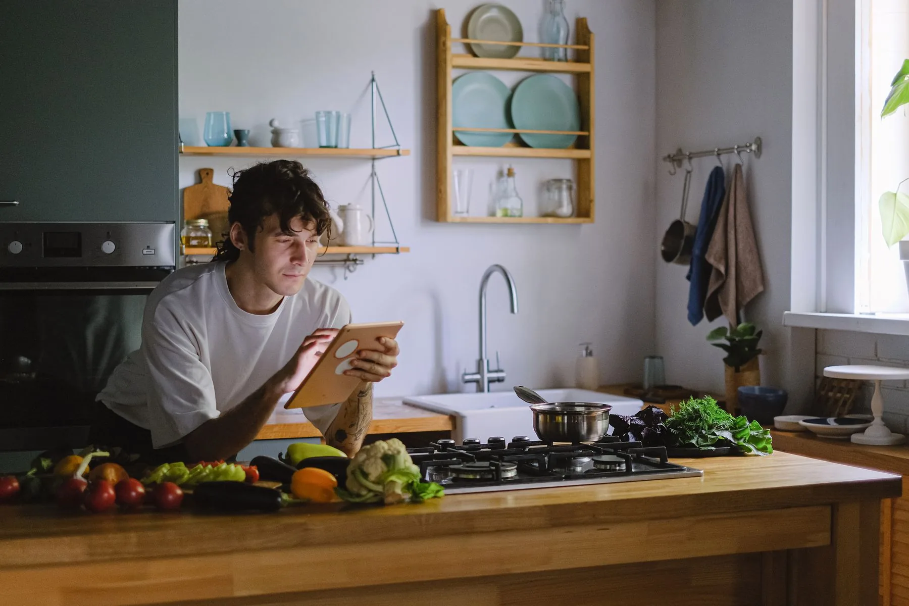 Person using a tablet while cooking in a modern kitchen
